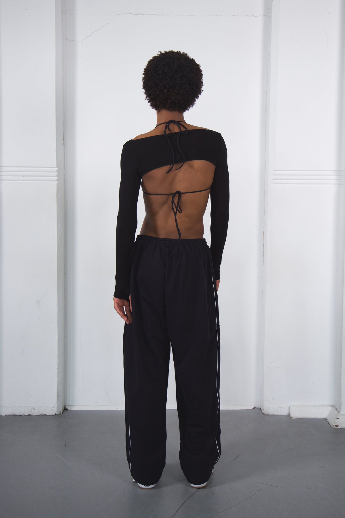 Person wearing a black dance outfit with cut-out design on a white background