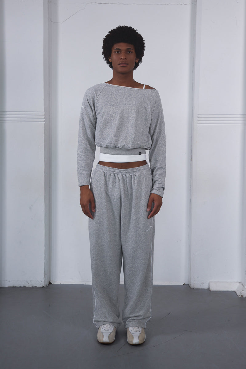 Person wearing a gray off-shoulder top and matching pants against a white background