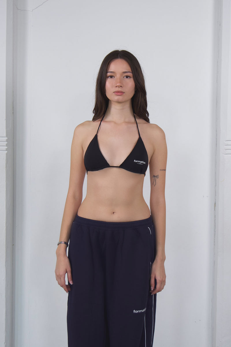 Woman wearing a black bikini top with a visible brand logo against a white background