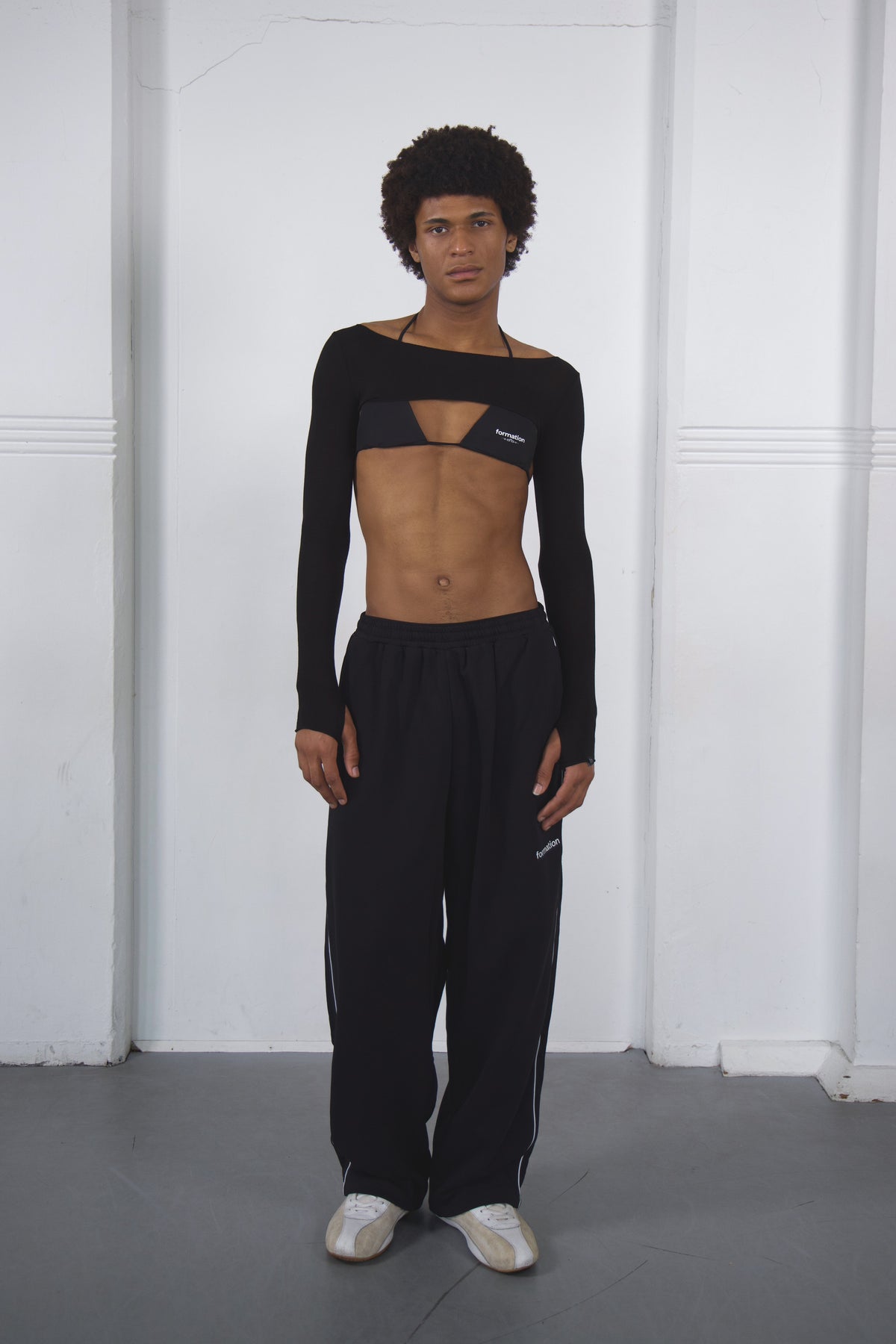 Person wearing a black long-sleeve top and pants with a brand logo against a white background