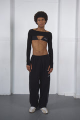 Person wearing a black long-sleeve top and pants with a brand logo against a white background