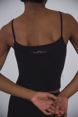 Black compression tank top with thin straps and subtle white logo on back