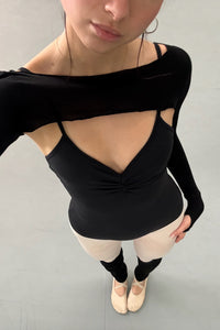 Person wearing a black bolero and black leotard in a dance studio. 