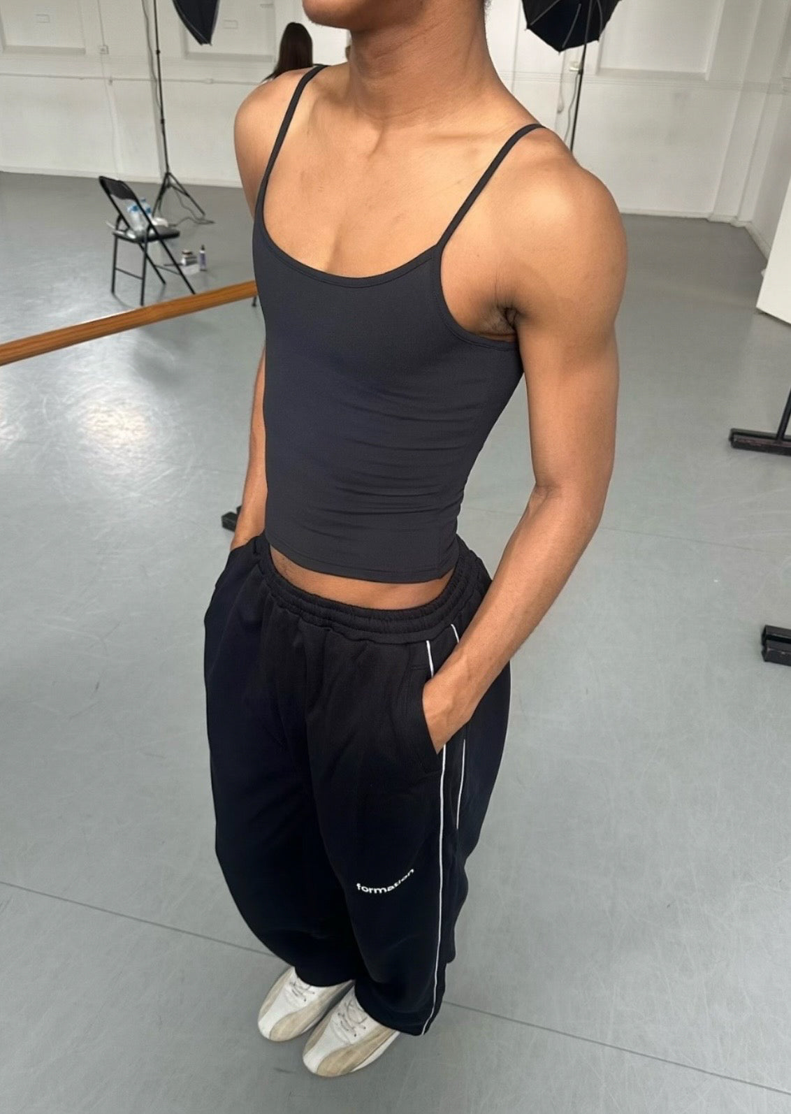 Person wearing a black tank top and black pants in a dance studio setting