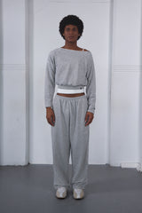 Person wearing a gray off-shoulder top and matching pants against a white background