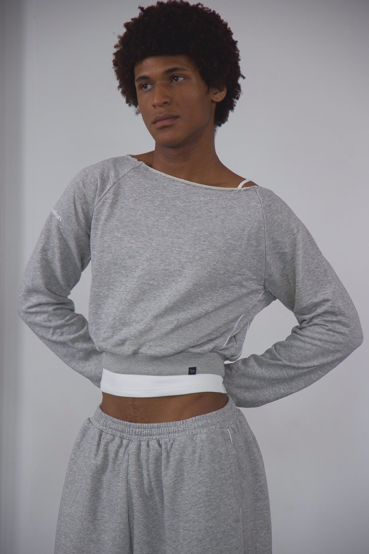Person wearing a gray long-sleeve top and gray sweatpants against a plain background
