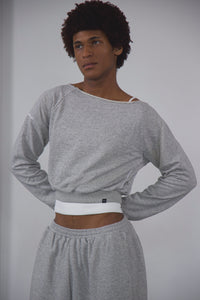 Person wearing a gray long-sleeve top and gray sweatpants against a plain background