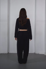 Person wearing a black outfit with a white wall background