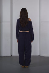 Person wearing a navy blue outfit standing against a white wall.