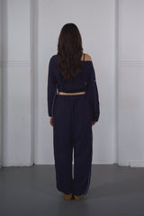 Person wearing a navy blue outfit standing against a white wall.