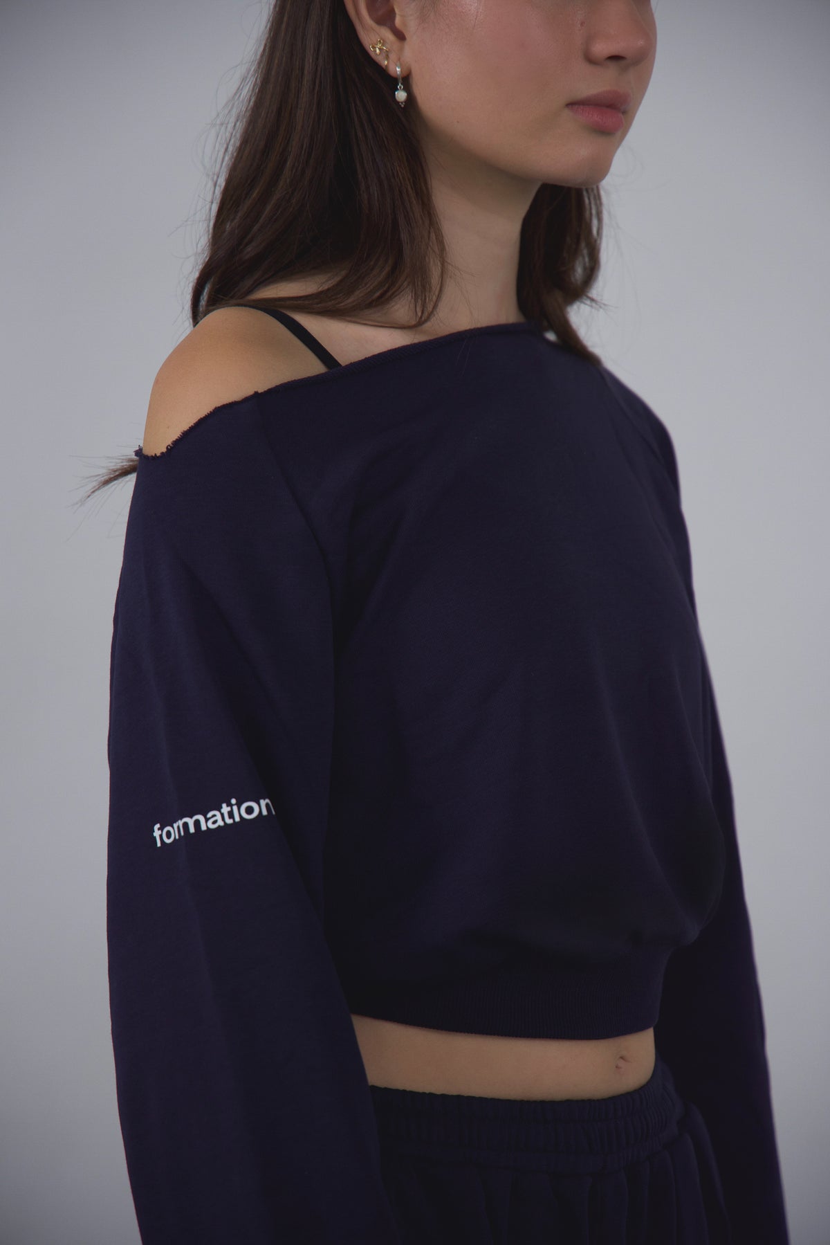 Person wearing a navy blue off-shoulder top with 'formation' text on a plain background