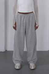 Person wearing a white top and gray pants against a plain white background