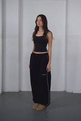 Woman wearing a black outfit with a white stripe on a plain background