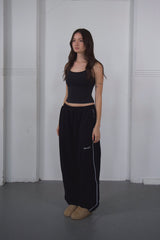 Woman wearing a black outfit with a white stripe on a plain background