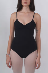 Woman wearing a black bodysuit against a plain background