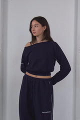 Woman wearing a navy blue outfit with a white wall background