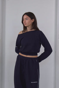 Woman wearing a navy blue outfit with a white wall background