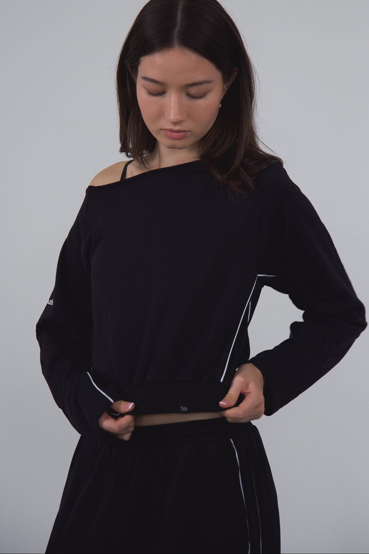 Woman wearing a navy off-shoulder top against a gray background