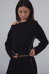 Woman wearing a navy off-shoulder top against a gray background