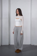 Woman wearing a white top and gray pants against a white background